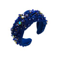 A navy blue knotted headband elegant adorned with sparkling blue and green crystals in a diamond-embedded high-grade design