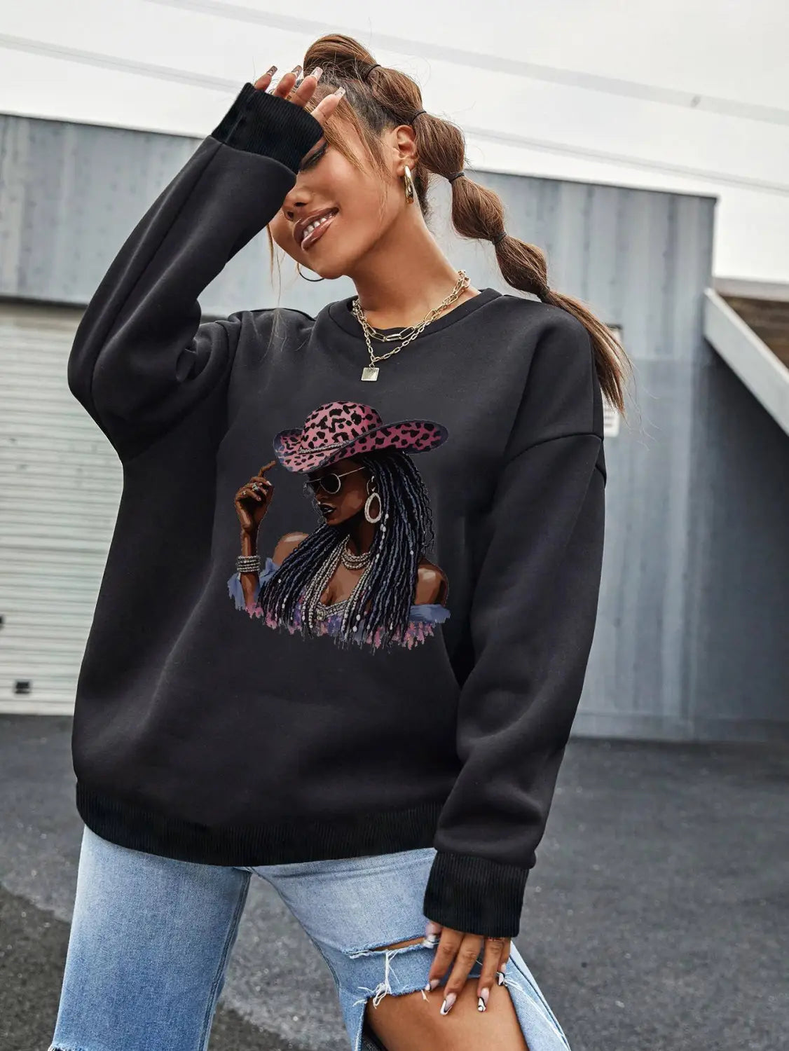 black oversized long sleeve sweatshirt featuring a vibrant graphic of a woman in a pink leopard-print hat and sunglasses.