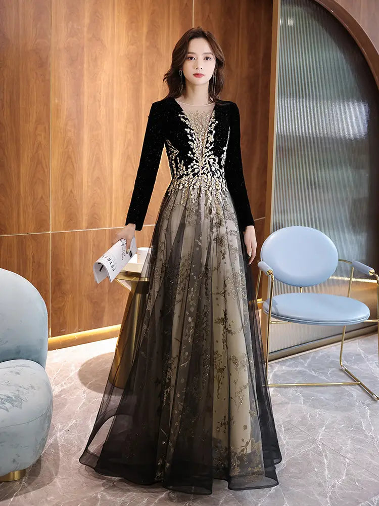 Elegant black moderator long velvet gown with long sleeve annual party design featuring gold embroidery and a sheer layered skirt.
