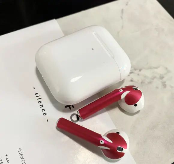 Red and white apple airpods 2 with a glossy finish featuring cartoonish face designs and a gold glossy custom sticker skin.