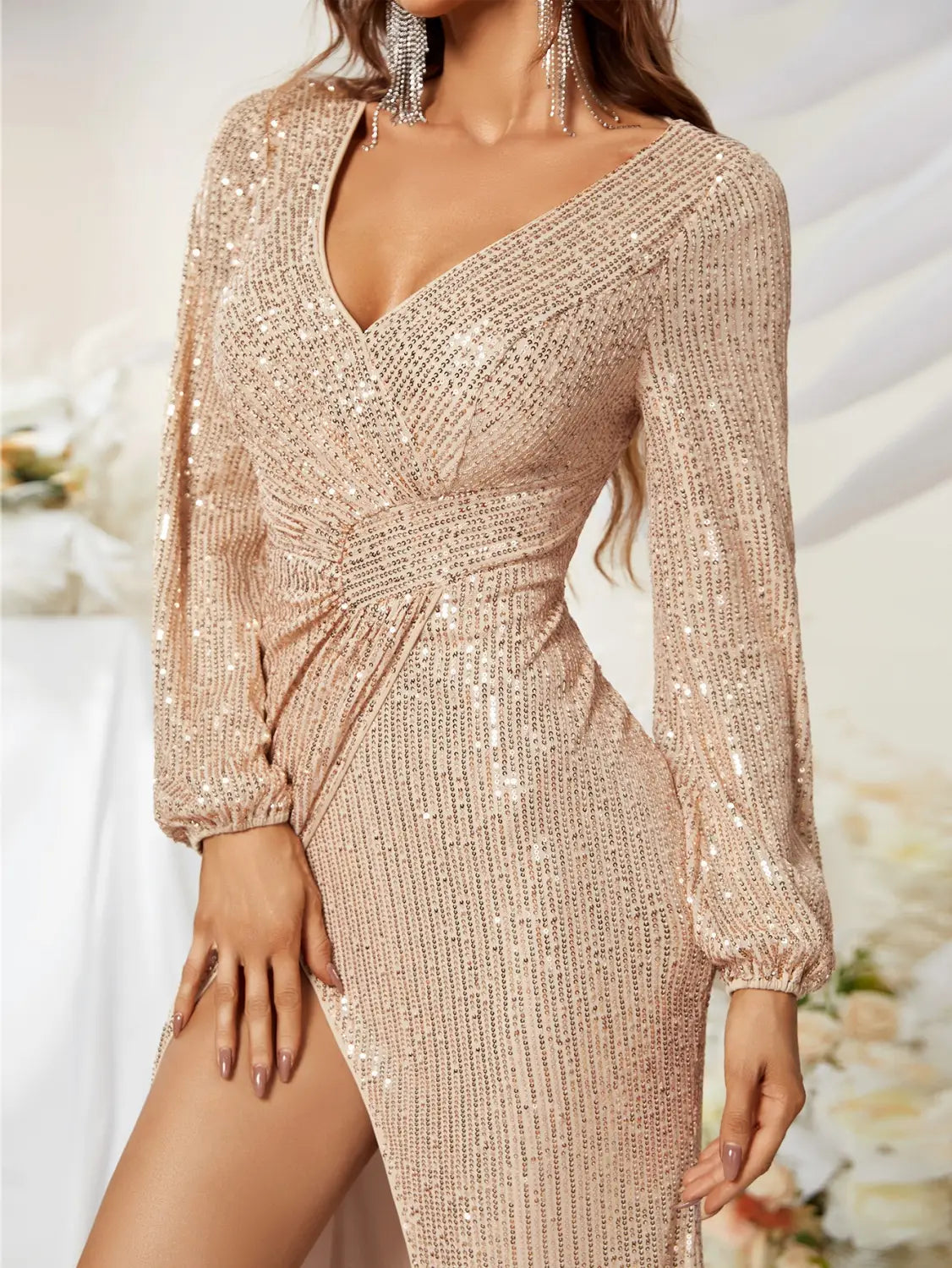 A shimmering rose gold sequined evening gown with long sleeves, a flattering v-neckline, and a long sleeve high slit fishtail design.