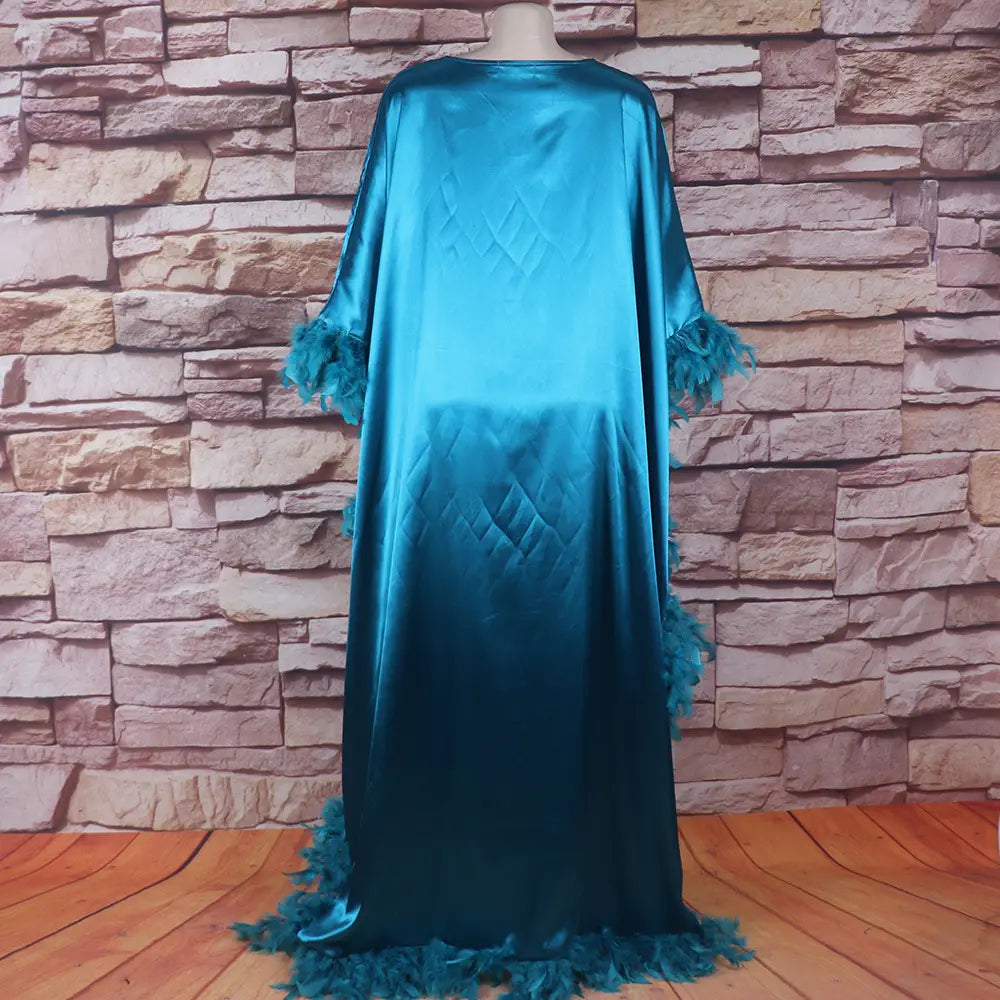 a flowing turquoise satin abaya loose dress luxury fully surrounded by feathered trim along the sleeves and hem