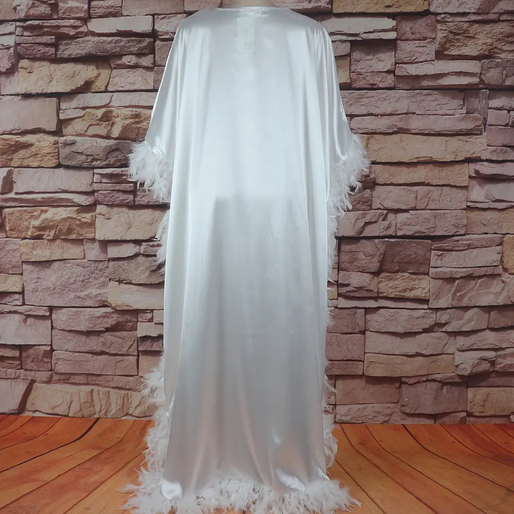 a flowing white satin loose dress luxury robe fully surrounded with delicate feather trim along the sleeves and hem
