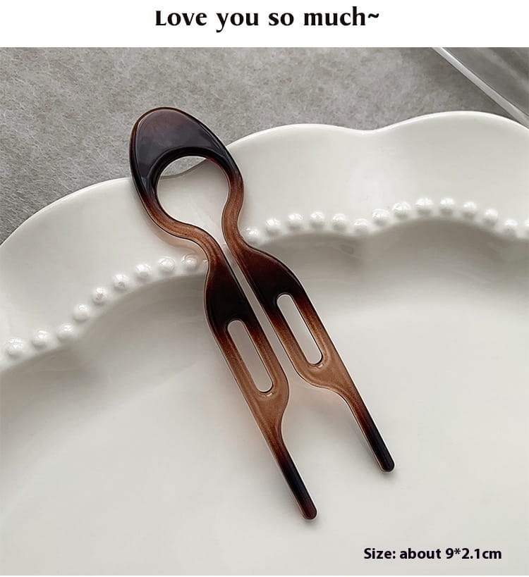 A sleek two-pronged hair comb with a gradient brown and black translucent plastic finish designed as a tortoiseshell bun lazy updo gadget for effortless head bun lazy styling.