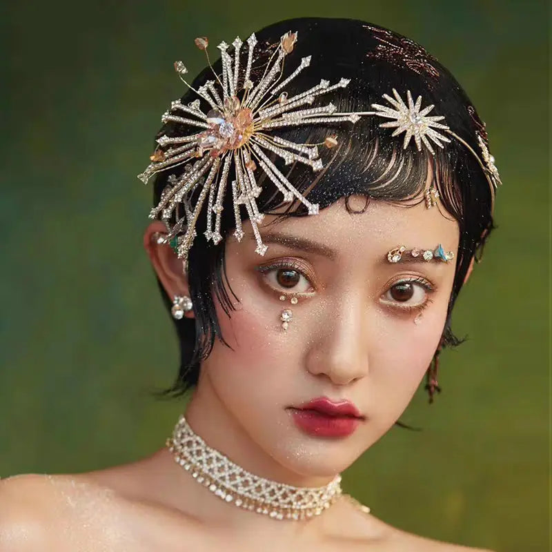 A sparkling silver starburst bridal rhinestone headband adorned with crystals and gold accents is an elegant hair accessory perfect for weddings.