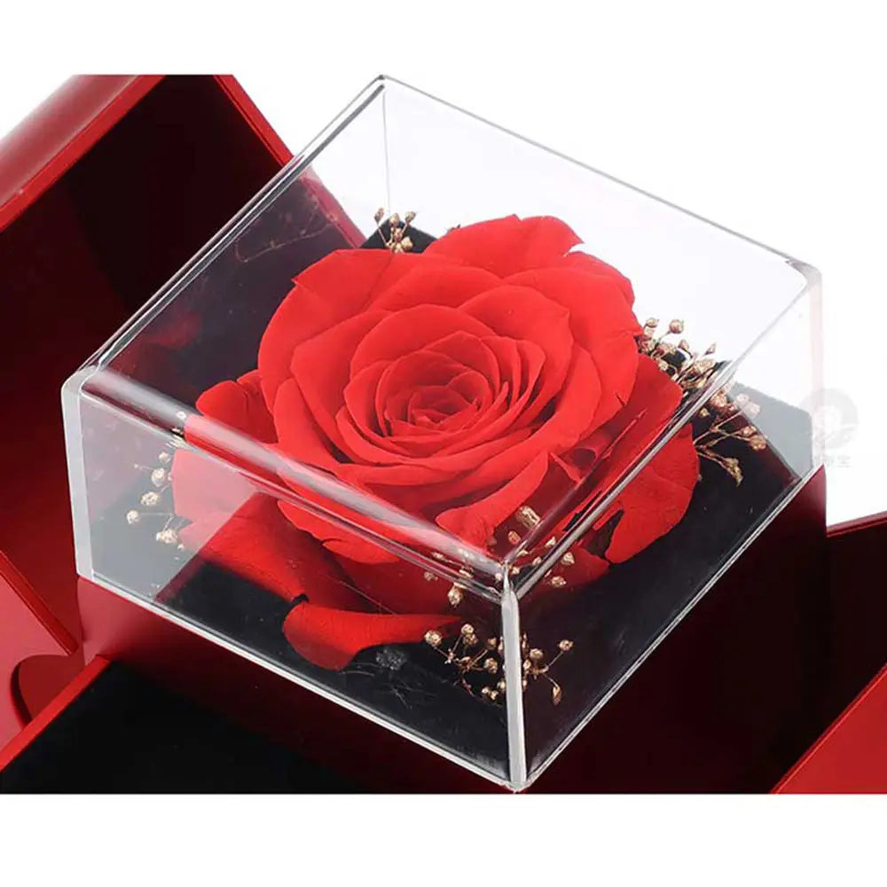 red apple jewelry box featuring a vibrant red preserved rose inside a clear acrylic cube accented with delicate gold-toned filler flowers.