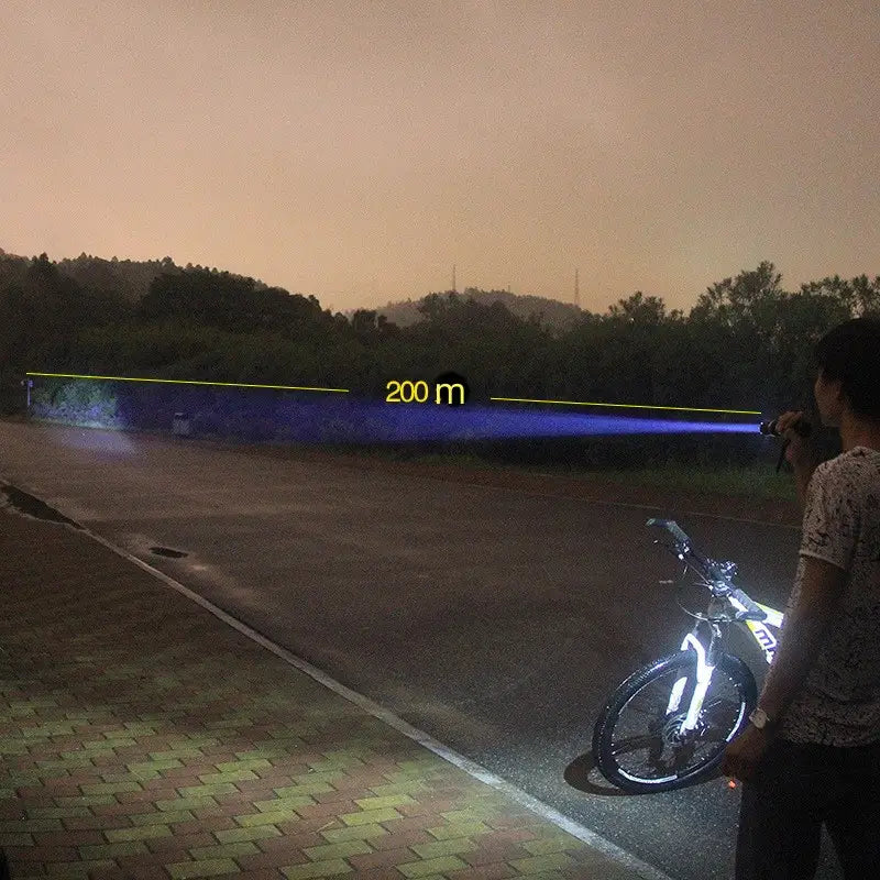 a powerful blue spiked tactical self-defense led flashlight emitting a 200-meter beam held by a person standing beside a bicycle on a paved path at dusk