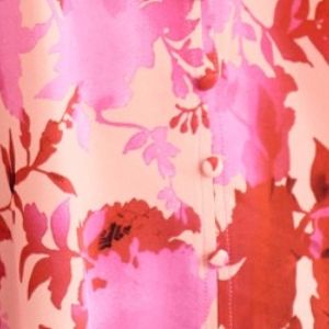 A vibrant pink and red decor button floral blouse made of soft flowing fabric featuring a decorative button detail.