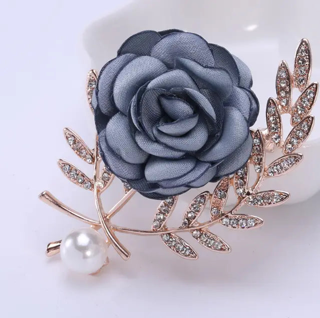 a delicate gray fabric flower lady brooch featuring rhinestone-encrusted gold-tone leaves and a pearl accent from the flower lady temperamental pin floral brooch set