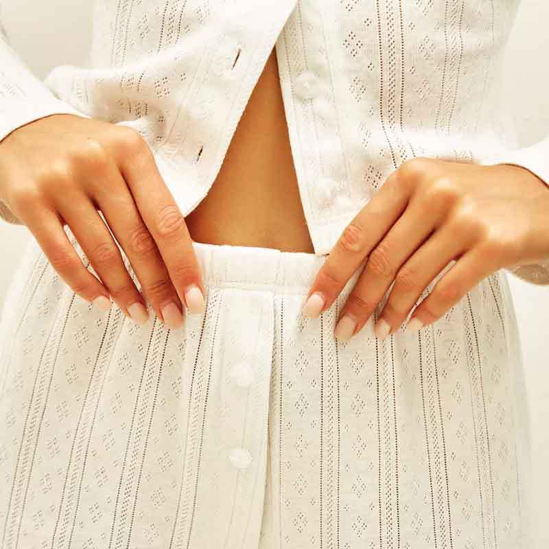 White eyelet lace long sleeve shirt with vertical striped patterns and pearl-like buttons paired with a white ribbed knit fashion cardigan long sleeve.