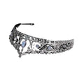 An ornate silver filigree bridal crown with clear crystals and a central blue gemstone for wedding makeup