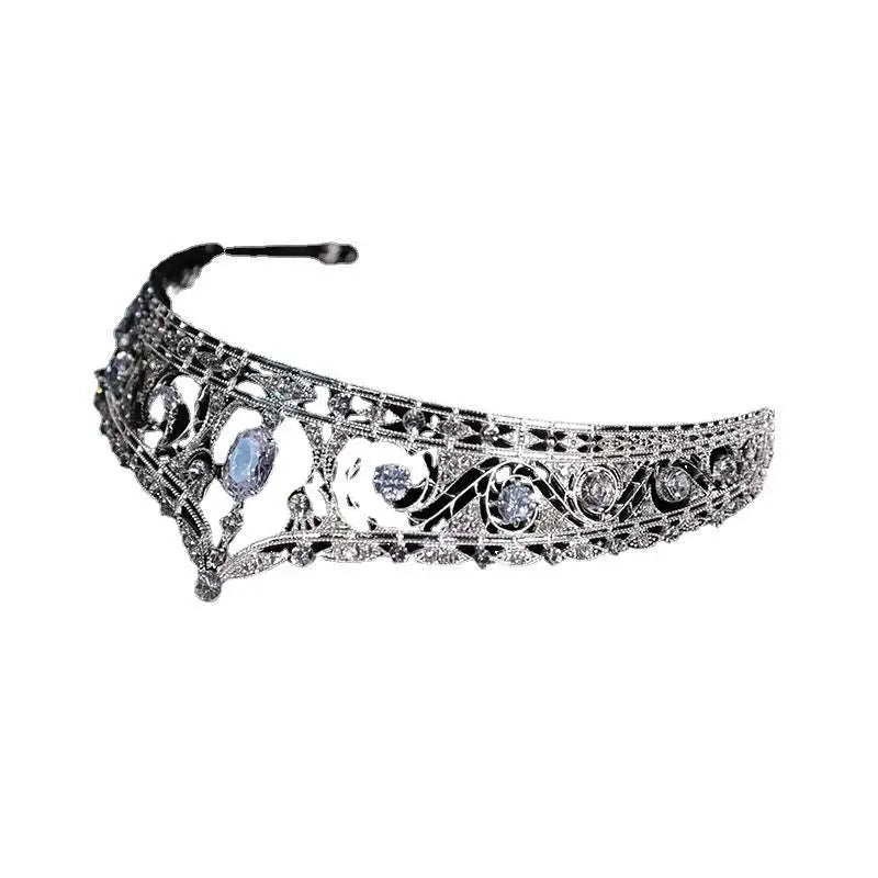 An ornate silver filigree bridal crown with clear crystals and a central blue gemstone for wedding makeup