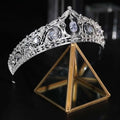An ornate silver filigree bridal crown with clear crystals and a central oval gemstone for wedding makeup