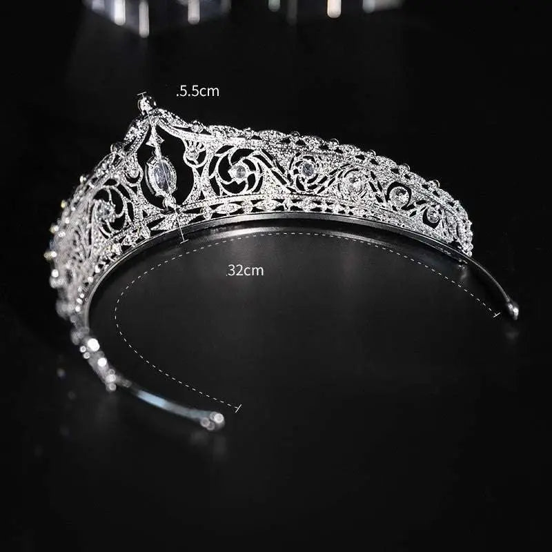 A silver filigree bridal crown with intricate patterns, embedded crystals, and a central oval gemstone for wedding makeup