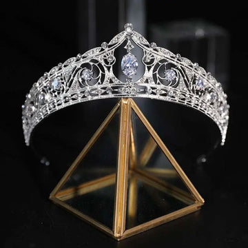An ornate silver filigree bridal crown with clear crystals and central oval gemstone for wedding makeup