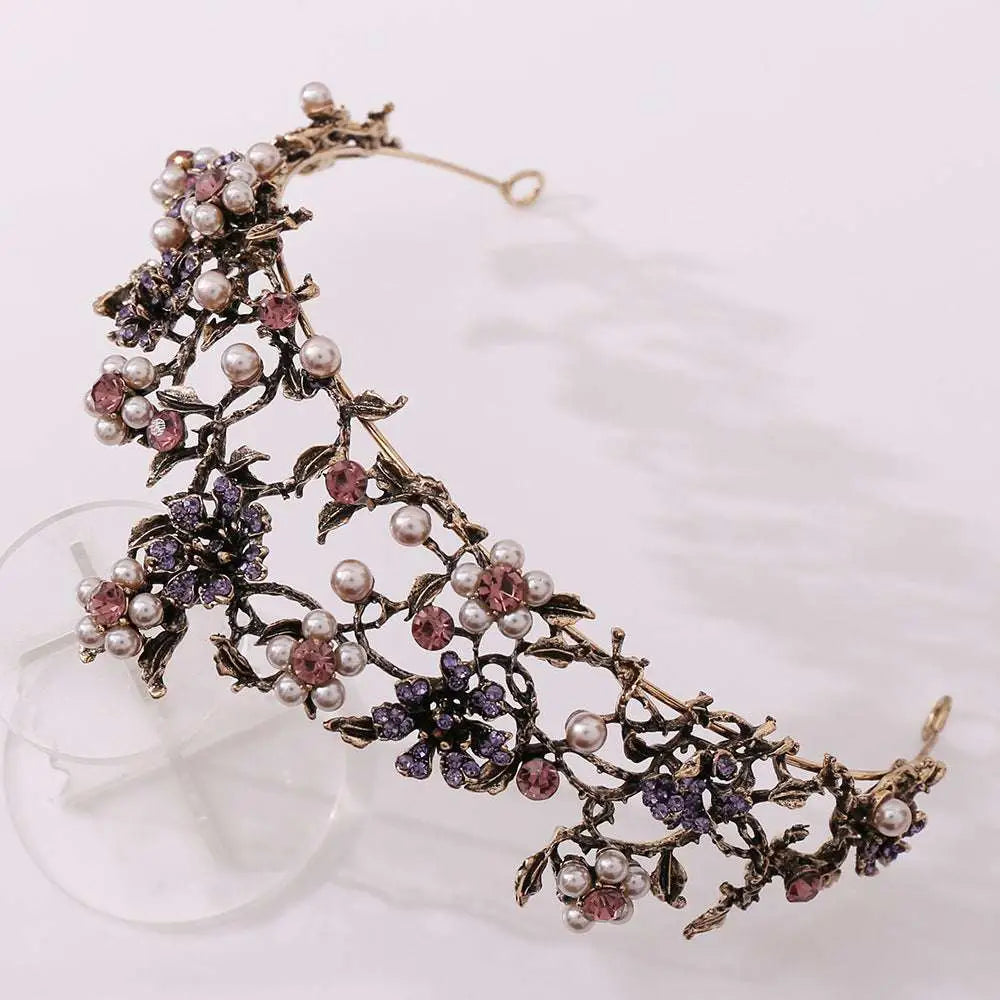 An ornate floral black diamond pearl baroque bridal crown with intricate metalwork, pink and purple crystals, and white pearls