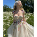 A delicate off-white champagne tulle prom dress with vibrant floral appliqués on the bodice and skirt