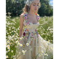 A delicate off-white champagne tulle prom dress with vibrant floral appliqués and a matching sheer headpiece