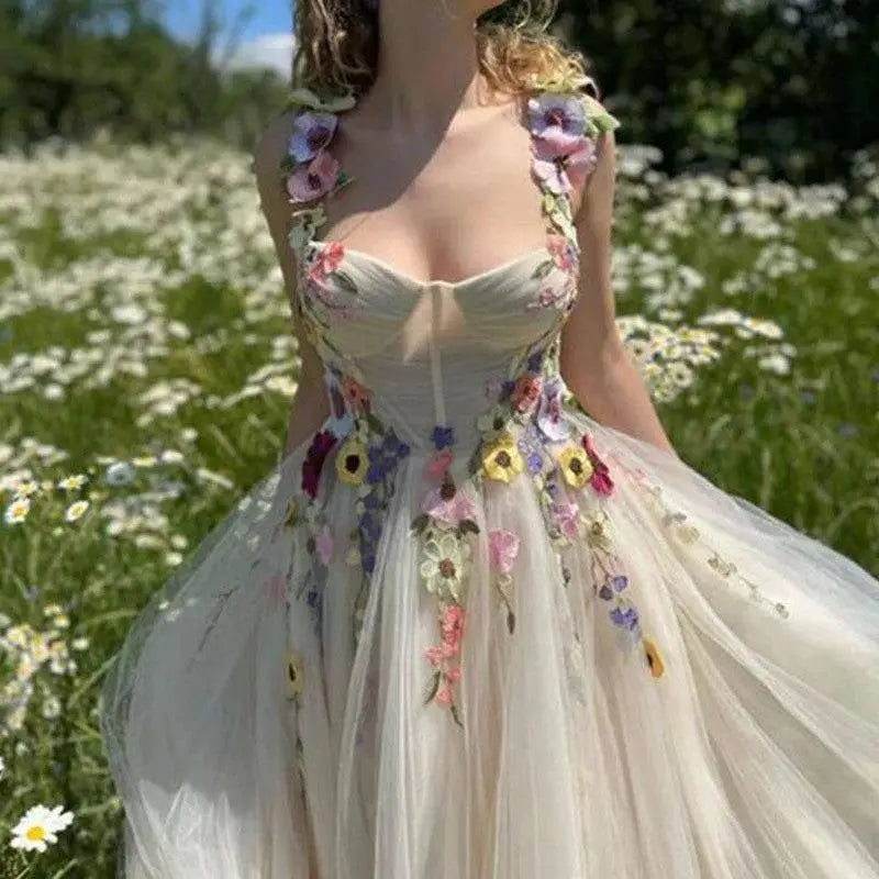 A delicate off-white champagne tulle prom dress with vibrant floral appliqués in pink purple yellow and blue