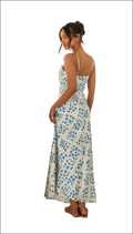 A white floral print maxi dress with delicate blue patterns, thin spaghetti straps, and a flattering swing skirt fit