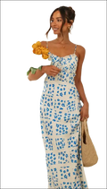 A woman wears a white floral print maxi dress with blue flowers and a swing skirt with thin spaghetti straps