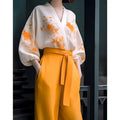 A floral silk slimming white blouse with vibrant orange embroidery and voluminous sleeves paired with mustard trousers in a flab hiding shirt set
