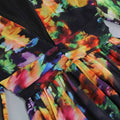 A vibrant floral v-neck split comfort casual dress with bold oranges purples and greens on a black background
