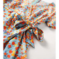 A light blue french floral slim polka dot wrap dress with vibrant orange yellow and purple blossoms tied at the waist