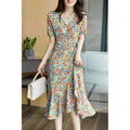 A woman wears a french floral slim polka dot wrap dress in light blue with orange and yellow blossoms and short sleeves