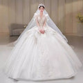 A voluminous white french retro bride wedding gown with intricate lace yarn long sleeve and a flowing veil