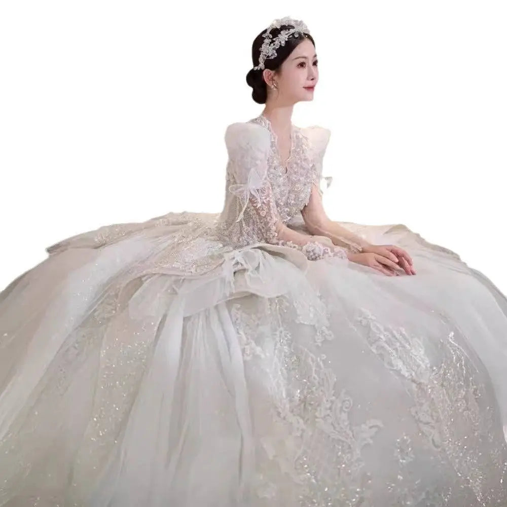 A voluminous white french retro bride wedding gown with intricate lace yarn long sleeve and a flowing veil