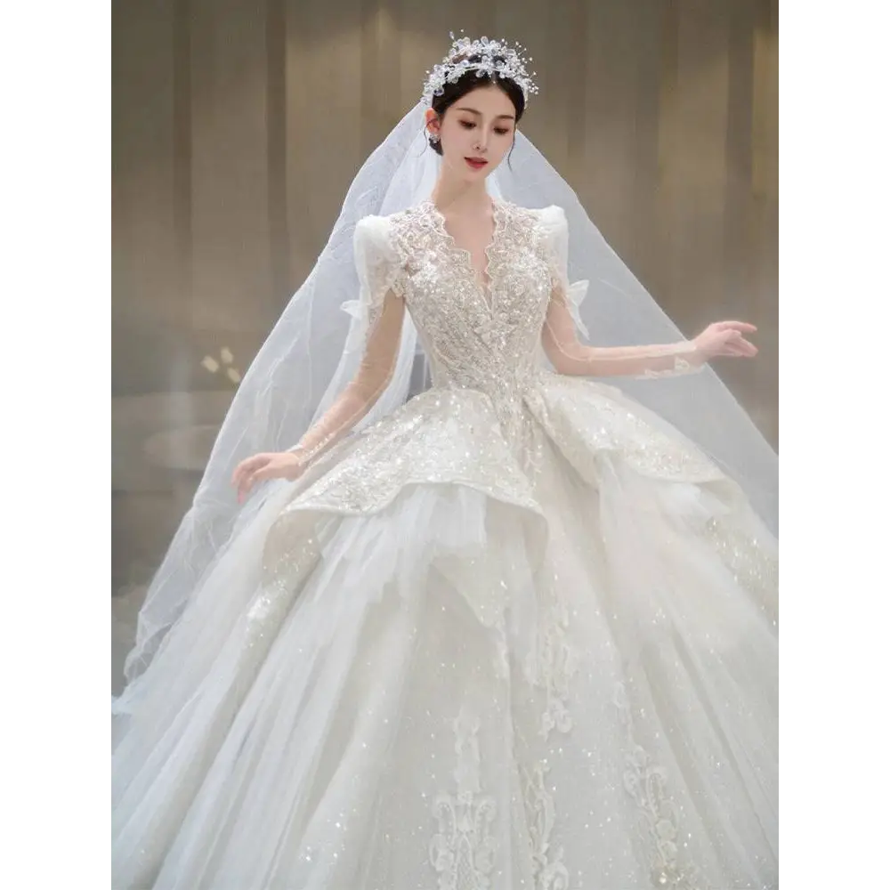 A sparkling white french retro bride wedding gown with yarn long sleeves, intricate beading, lace, and a voluminous skirt