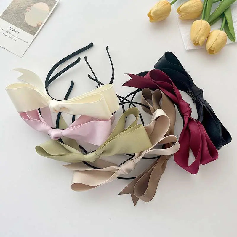 A collection of french satin bow headbands in pastel and deep burgundy hues featuring large satin bows