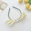 French satin bow headband for women featuring a delicate cream satin bow on a sleek black bow headband