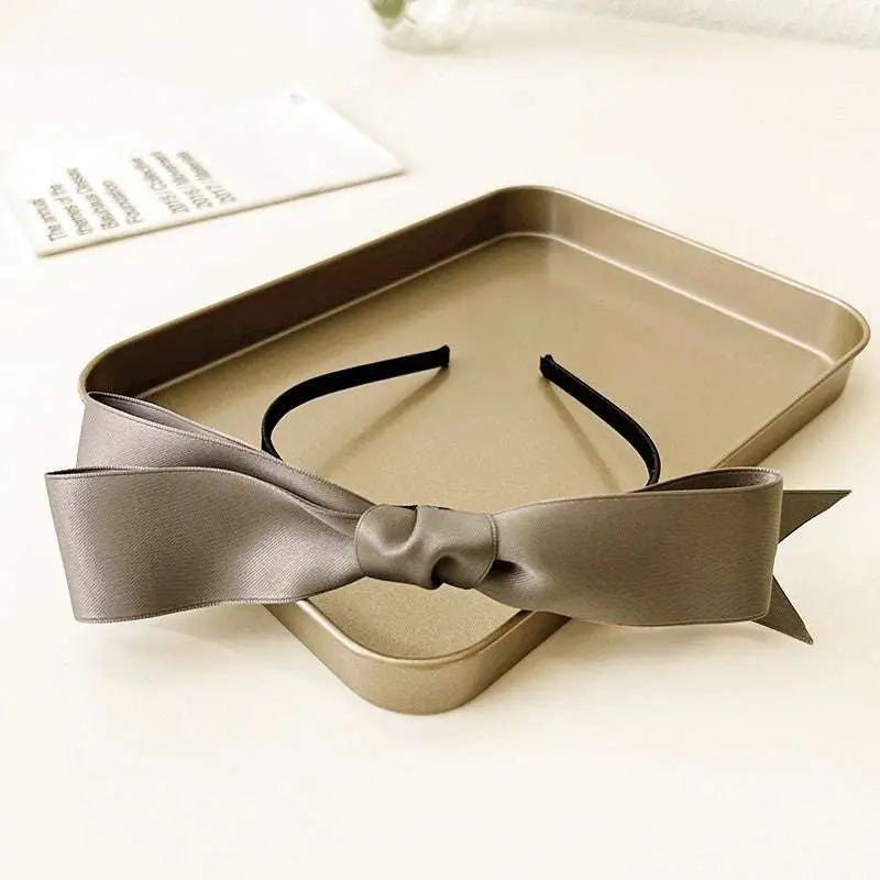 A sleek matte gray french satin bow headband featuring a soft glossy finish and a neatly tied knot for women