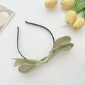Delicate sage green french satin bow headband with a sleek black satin bow headband elastic band for women
