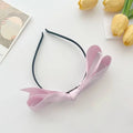 A delicate pink french satin bow adorns a sleek black satin bow headband for women
