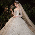 A sparkling white wedding evening gown from the temperament dream collection with long sheer sleeves and sequined bodice