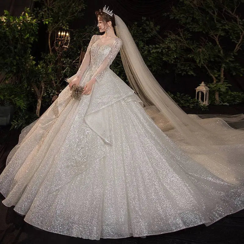 A sparkling white wedding evening gown from the French Temperament Dream collection with long sheer sleeves and beading