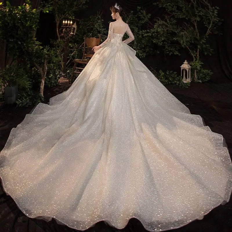 A shimmering ivory french temperament dream wedding evening dress with fitted bodice long sleeves and sequin train