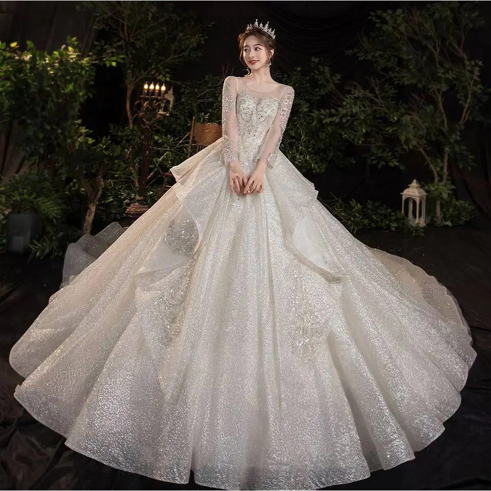 A sparkling white wedding evening gown from the temperament dream collection with long sheer sleeves and tulle skirt