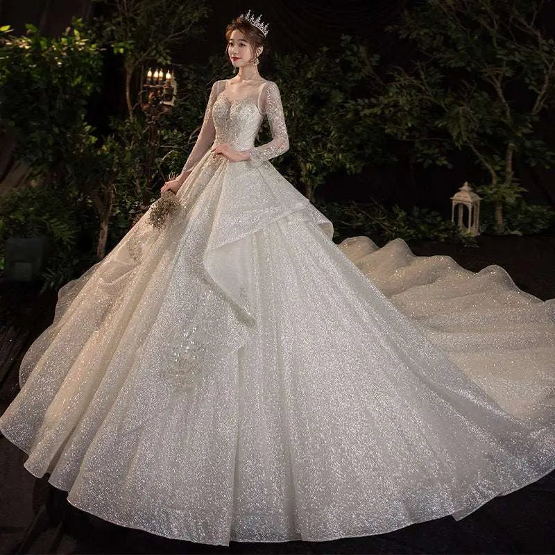 A sparkling white wedding evening gown from the temperament dream collection with long sheer sleeves and sequined bodice