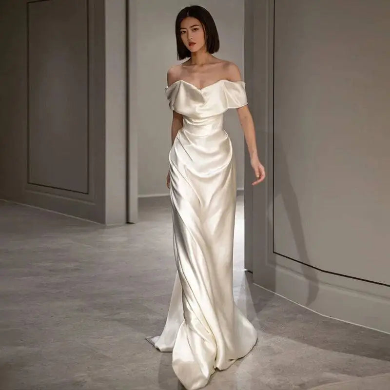 A french white off-shoulder satin wedding dress in soft ivory with elegant draping and a sleek silhouette