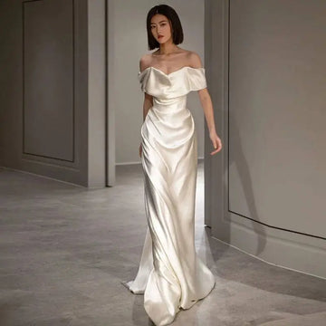 A french white off-shoulder satin wedding dress in soft ivory with elegant draping and a sleek silhouette