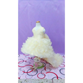 A delicate ivory ruffled flower girl tuxedo dress with fitted bodice and voluminous skirt on mannequin