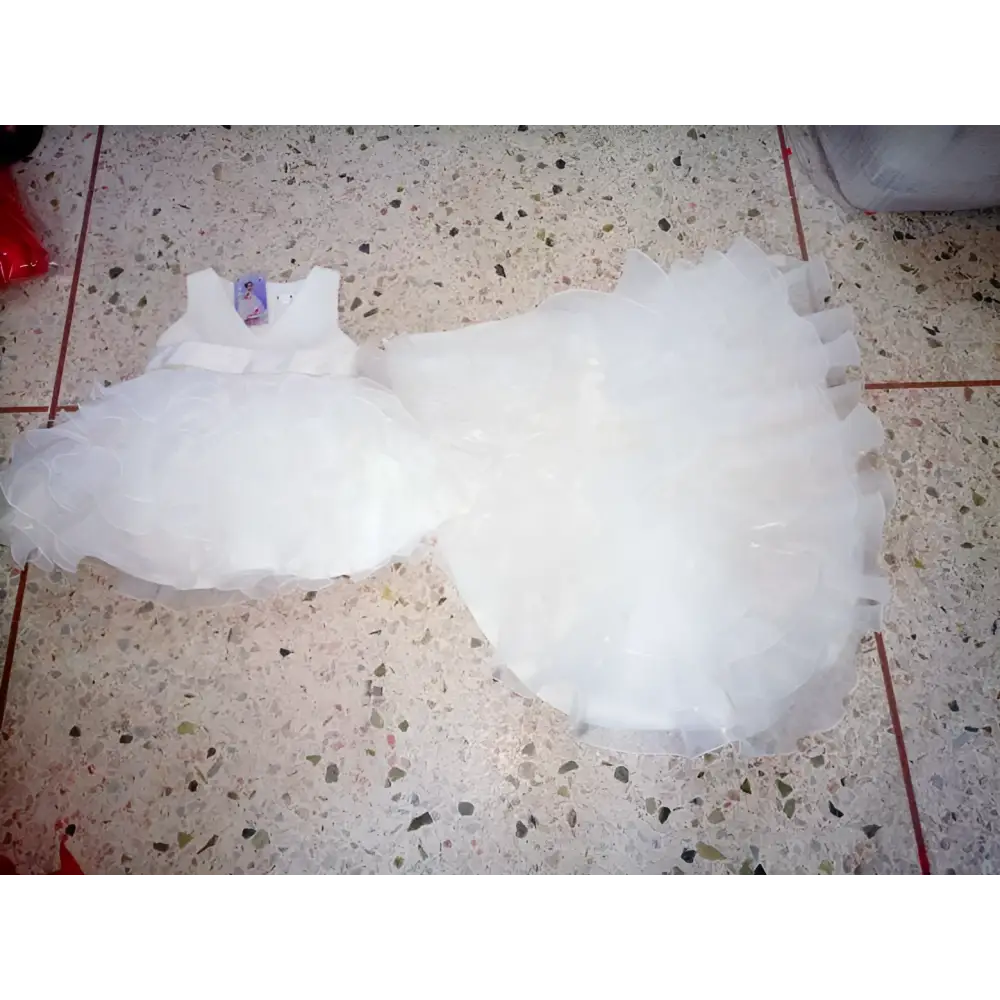 A delicate white tulle flower girl tuxedo with fitted bodice and layered ruffles in the fuchsia layered ruffled style