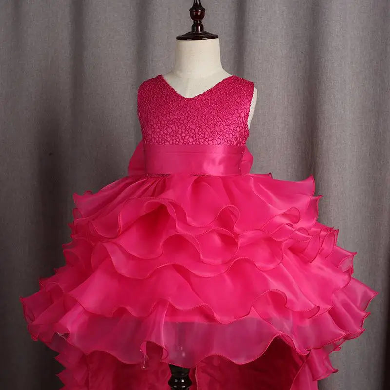 A vibrant fuchsia layered ruffled flower girl tuxedo with a sleeveless lace bodice and trailing skirt