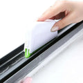 White plastic gap brush with green bristles and sponge scrubber designed for cleaning window grooves