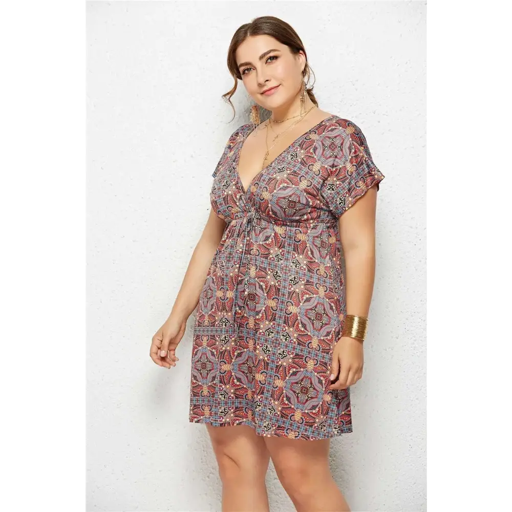 A plus-size woman wearing a printed deep v-neck geometric printed deep elastic waist dress in red beige and gray tones