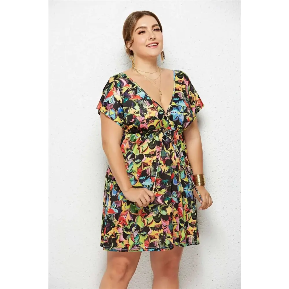 A vibrant short-sleeved geometric printed deep v-neck dress with bold multicolored abstract leaf pattern on black fabric